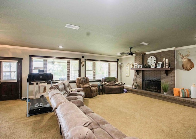 carpeted living room featuring a textured ceiling, ceiling fan, crown molding, and a brick fireplace