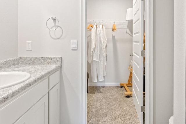 bathroom with a walk in closet and vanity