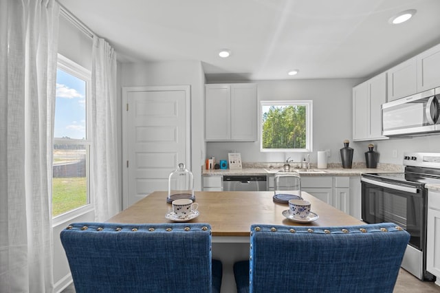 kitchen featuring stainless steel appliances, recessed lighting, white cabinetry, a kitchen island, and a sink