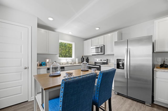 kitchen featuring recessed lighting, butcher block countertops, white cabinetry, appliances with stainless steel finishes, and light wood-type flooring