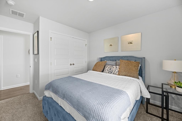 bedroom with a closet, carpet, visible vents, and baseboards