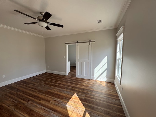 unfurnished room featuring a barn door, ornamental molding, dark wood finished floors, and a ceiling fan