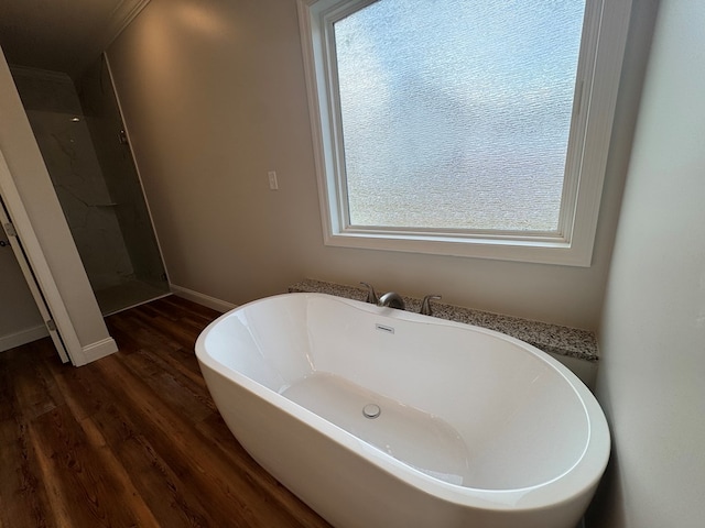 full bathroom with a walk in shower, a freestanding bath, baseboards, and wood finished floors