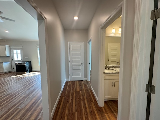 hall with dark wood-style floors, a sink, and baseboards