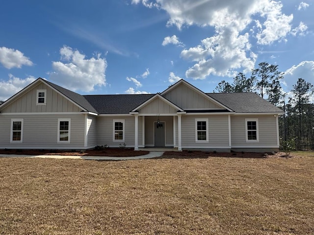 view of front of house featuring board and batten siding, a shingled roof, and a front lawn