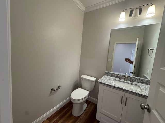 half bath with toilet, ornamental molding, vanity, wood finished floors, and baseboards