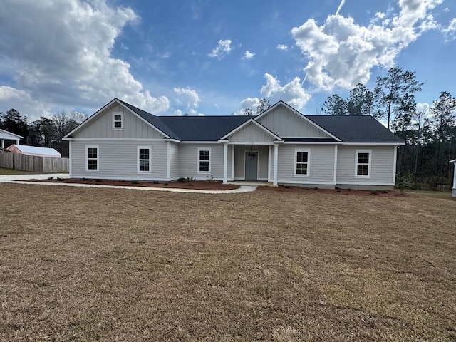 view of front of property featuring roof with shingles, fence, a porch, board and batten siding, and a front yard