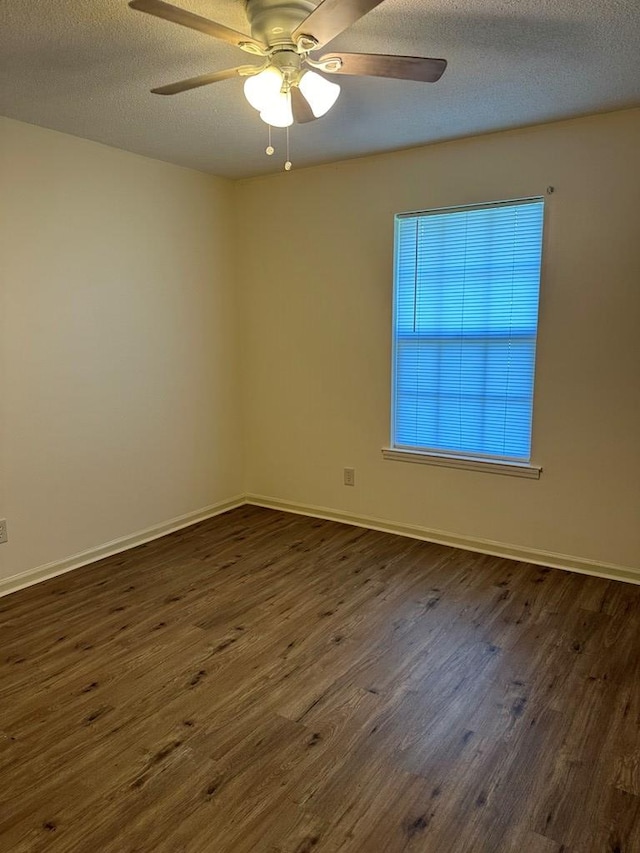 empty room featuring dark hardwood / wood-style floors, ceiling fan, and a textured ceiling