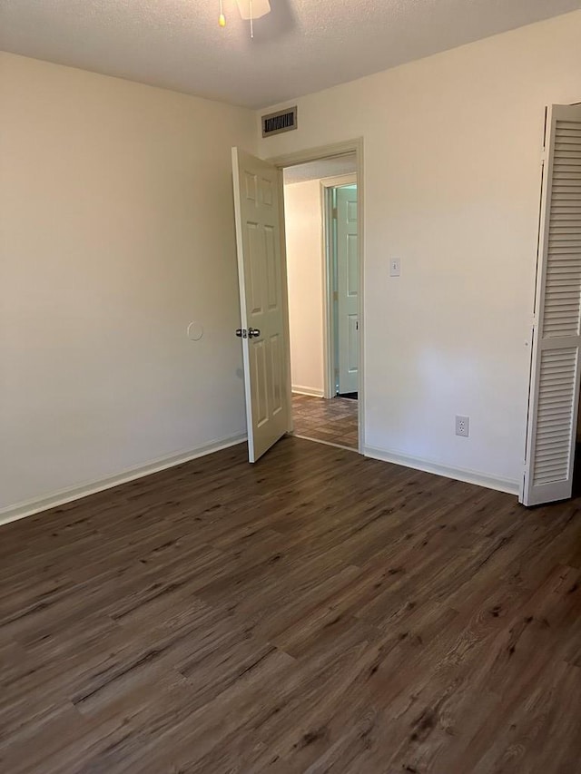 spare room with dark hardwood / wood-style floors and a textured ceiling