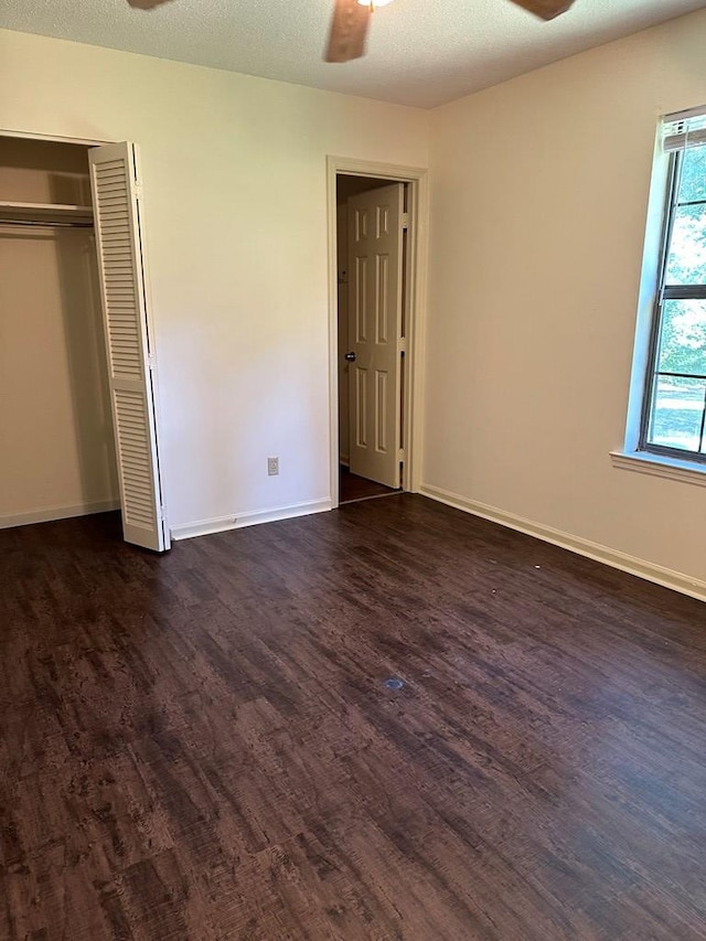 unfurnished bedroom featuring a textured ceiling, a closet, ceiling fan, and dark wood-type flooring