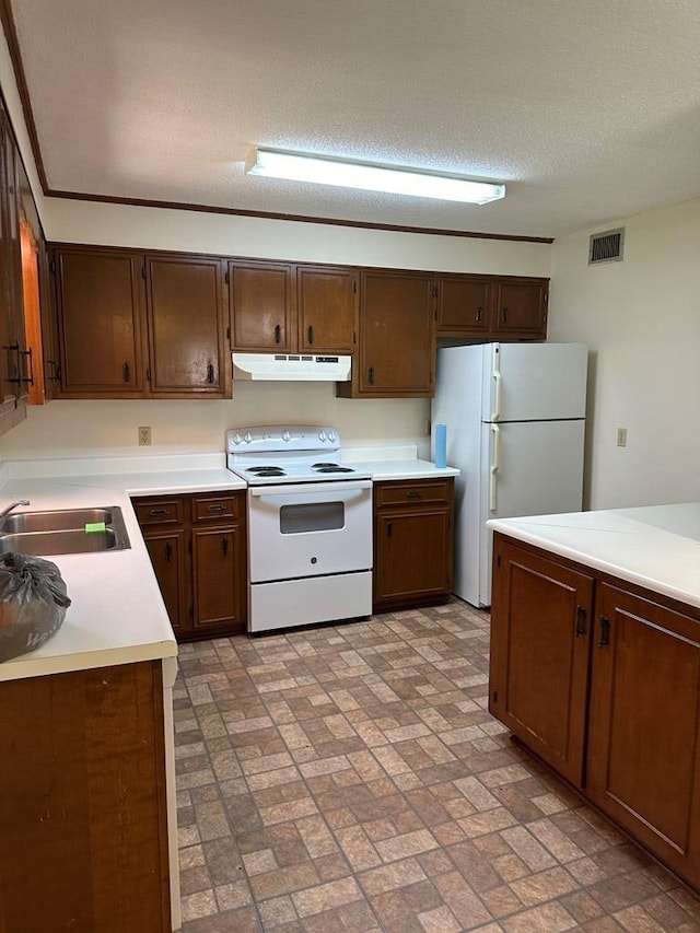 kitchen featuring a textured ceiling, white appliances, and sink