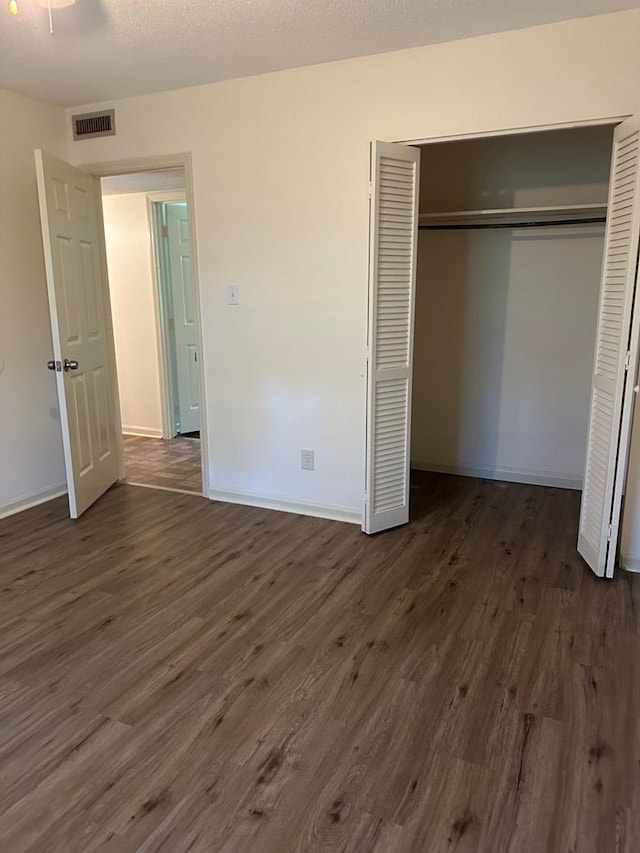 unfurnished bedroom with dark hardwood / wood-style flooring and a closet