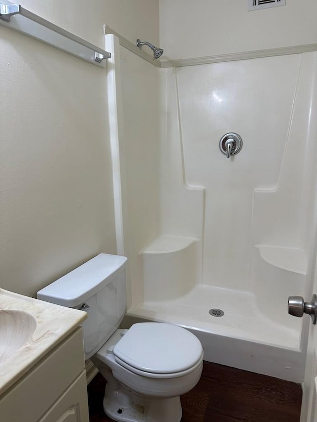 bathroom with a shower, vanity, wood-type flooring, and toilet