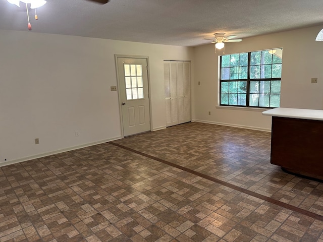 unfurnished living room featuring a textured ceiling and ceiling fan