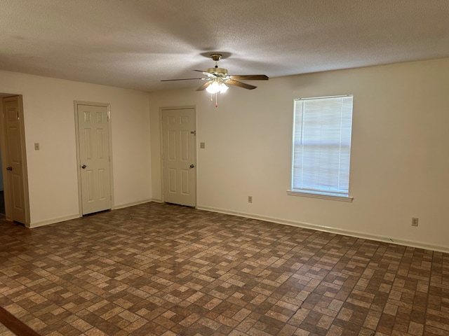 empty room with ceiling fan and a textured ceiling