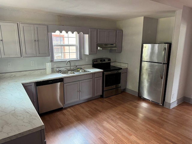 kitchen featuring light wood-type flooring, stainless steel appliances, gray cabinets, and sink