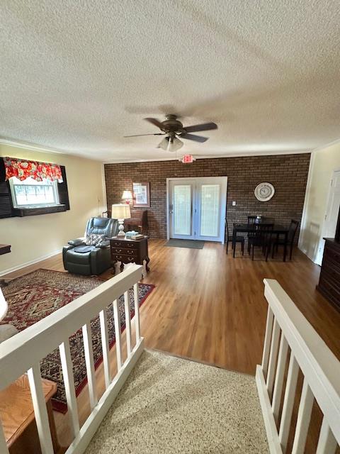 living room with brick wall, a healthy amount of sunlight, and a textured ceiling