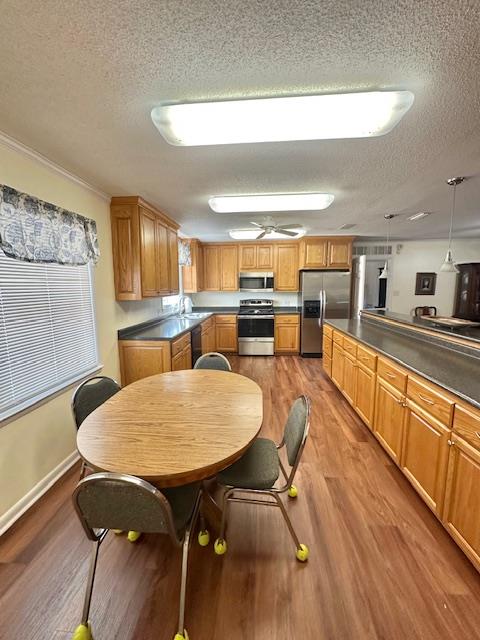 kitchen with hanging light fixtures, light hardwood / wood-style floors, a textured ceiling, and appliances with stainless steel finishes