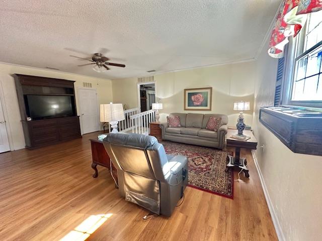 living room with wood-type flooring, ceiling fan, and a textured ceiling