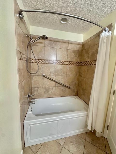 bathroom featuring tile patterned floors, shower / tub combo, and a textured ceiling