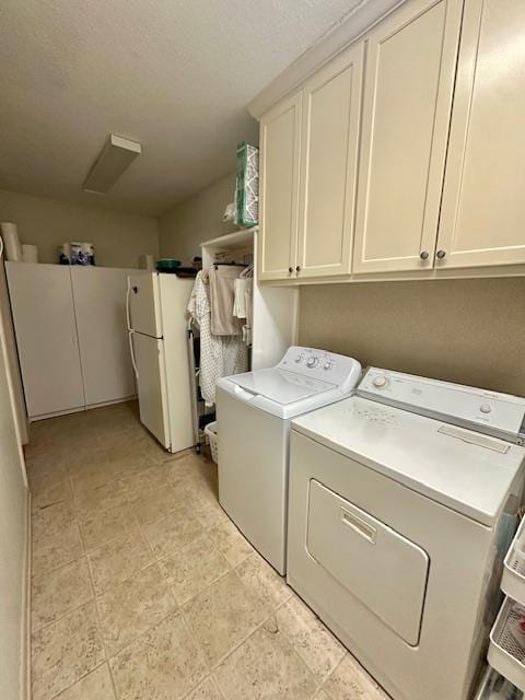 clothes washing area featuring cabinets and washing machine and clothes dryer