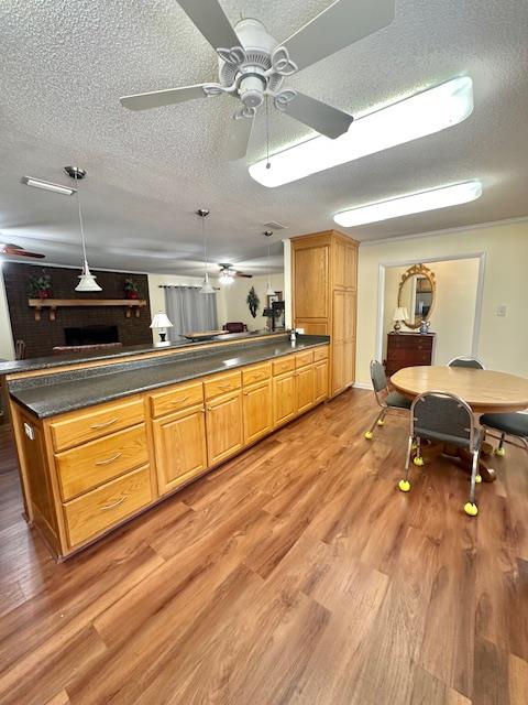 kitchen featuring pendant lighting, ceiling fan, a textured ceiling, and light wood-type flooring