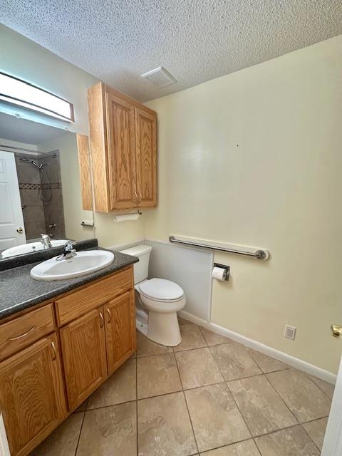 bathroom featuring tile patterned flooring, vanity, a textured ceiling, a shower, and toilet