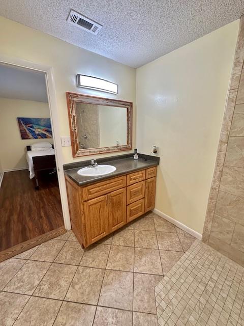 bathroom with tile patterned floors, a textured ceiling, and vanity