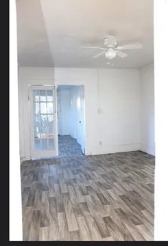 unfurnished room with ceiling fan and dark wood-type flooring