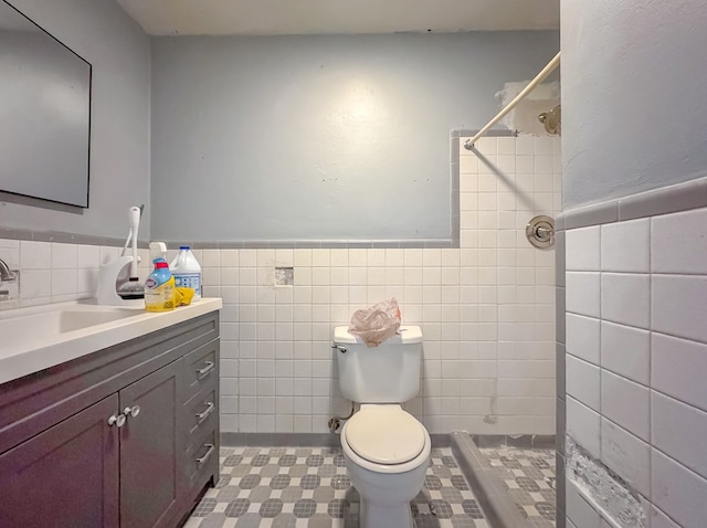 bathroom with tile walls, toilet, walk in shower, and vanity