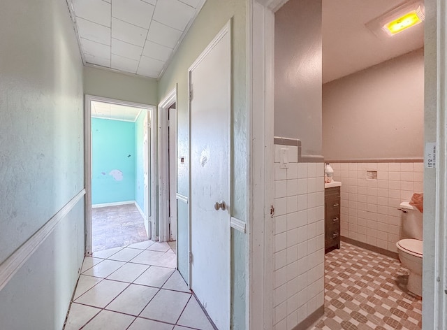 corridor with tile walls and light tile patterned floors