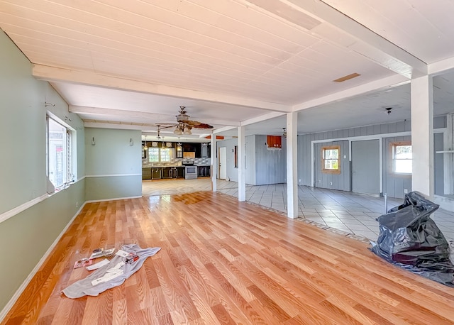 unfurnished living room featuring ceiling fan, light hardwood / wood-style flooring, and beamed ceiling