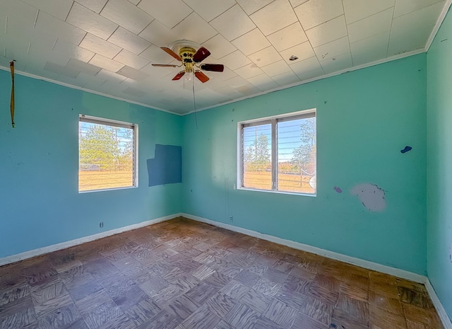 spare room featuring ceiling fan, crown molding, parquet floors, and plenty of natural light