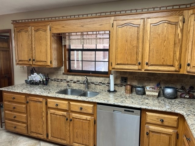 kitchen with sink, tasteful backsplash, light stone counters, stainless steel dishwasher, and light tile patterned flooring