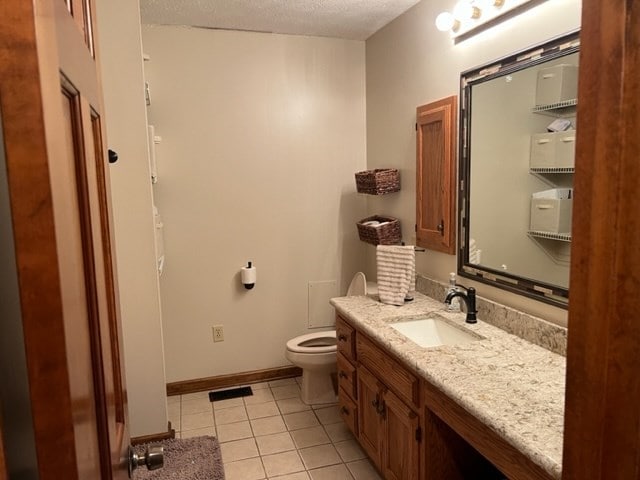 bathroom featuring tile patterned flooring, vanity, a textured ceiling, and toilet