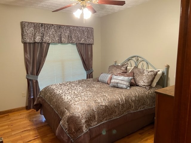 bedroom with ceiling fan, a textured ceiling, and light hardwood / wood-style flooring