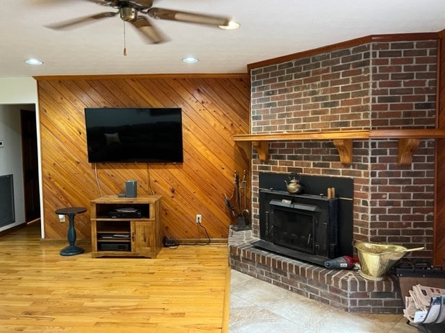 living room featuring a brick fireplace, wooden walls, ceiling fan, and hardwood / wood-style flooring