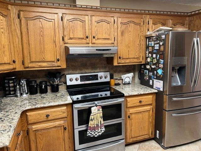 kitchen with light stone counters, light tile patterned floors, backsplash, and appliances with stainless steel finishes