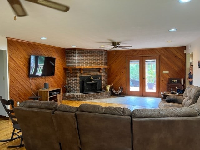 living room with hardwood / wood-style floors, ceiling fan, french doors, and wood walls