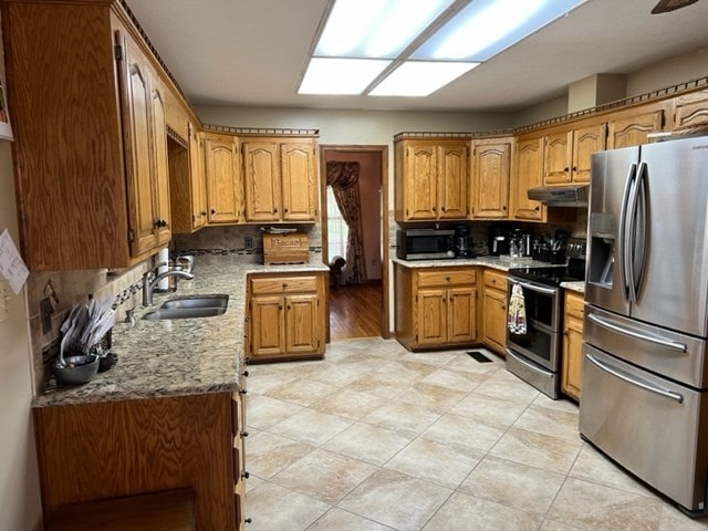 267 Providence Rd, Whigham, GA 39897 - kitchen with appliances with stainless steel finishes, a sink, backsplash, brown cabinets, and under cabinet range hood