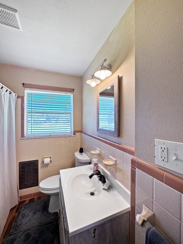 810 Three Notch Rd, Colquitt, GA 39837 - full bath featuring visible vents, tile walls, toilet, vanity, and a textured ceiling