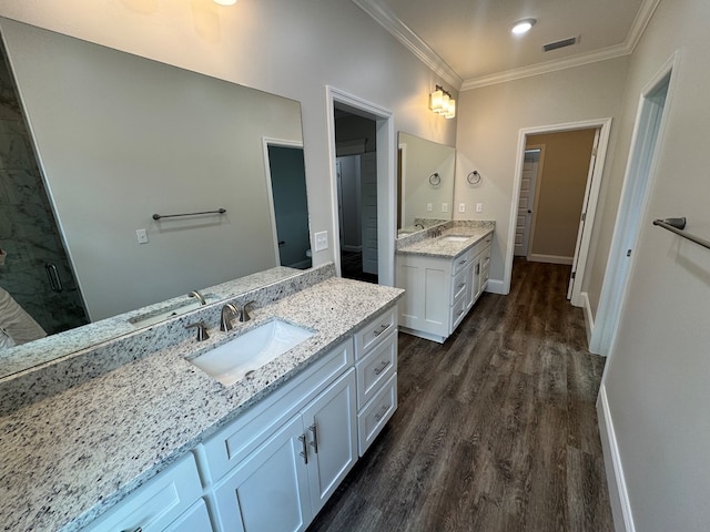 full bath with ornamental molding, two vanities, a sink, and wood finished floors