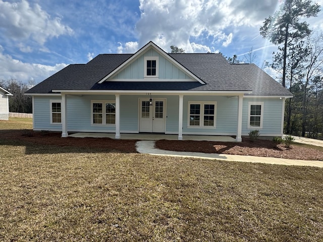 view of front of home featuring covered porch, roof with shingles, board and batten siding, and a front yard