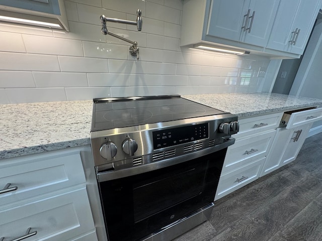 kitchen with stainless steel electric range, light stone counters, decorative backsplash, and dark wood finished floors