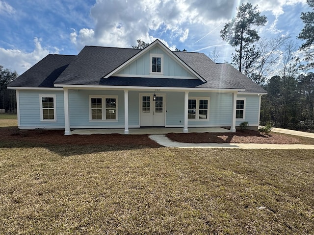 view of front of house featuring roof with shingles, covered porch, french doors, a front lawn, and board and batten siding