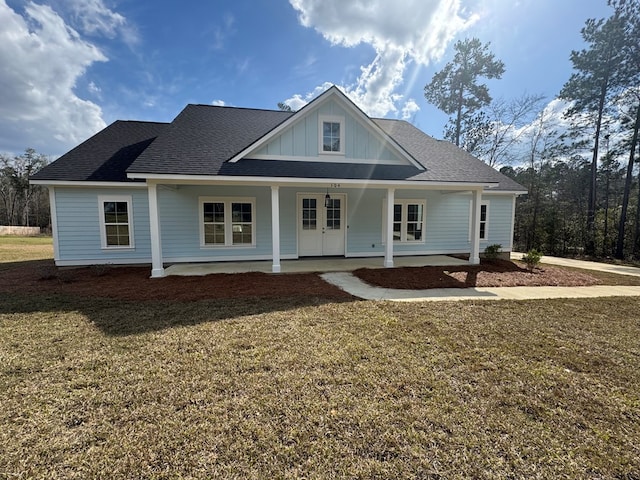 view of front of home with board and batten siding, french doors, a porch, and a front lawn