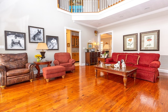 living room featuring crown molding, a towering ceiling, and hardwood / wood-style flooring