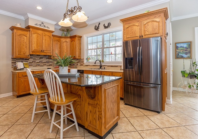 kitchen with crown molding, sink, stainless steel fridge, light tile patterned floors, and a kitchen island