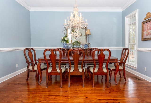 dining room with hardwood / wood-style floors, crown molding, and a notable chandelier