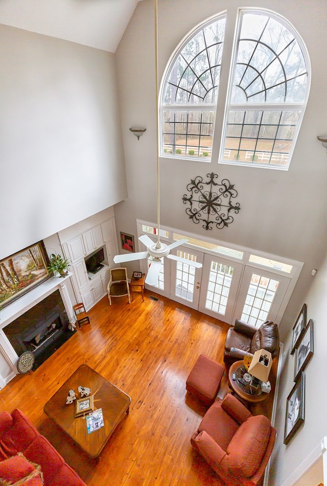 living room featuring a fireplace, a towering ceiling, and hardwood / wood-style flooring